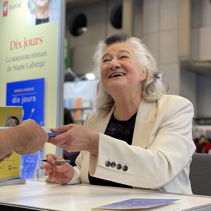 Une femme tient un crayon &agrave; la main et sourit.