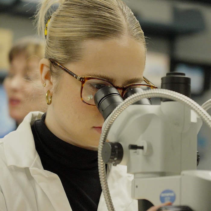 Une femme en sarrau travaille avec un microscope dans un laboratoire.