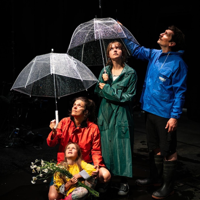 Un père, une mère et leurs deux filles sont sous des parapluies.