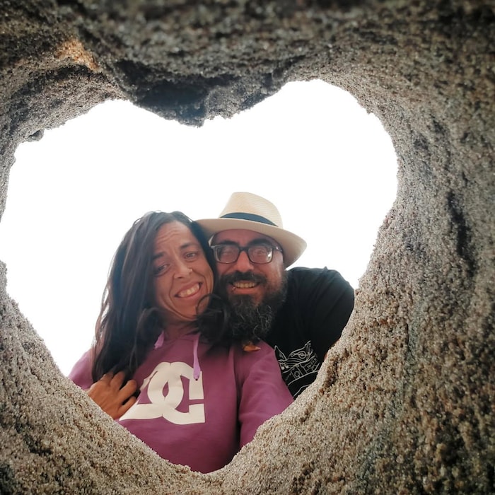 Deux personnes regardent dans un coeur en sable