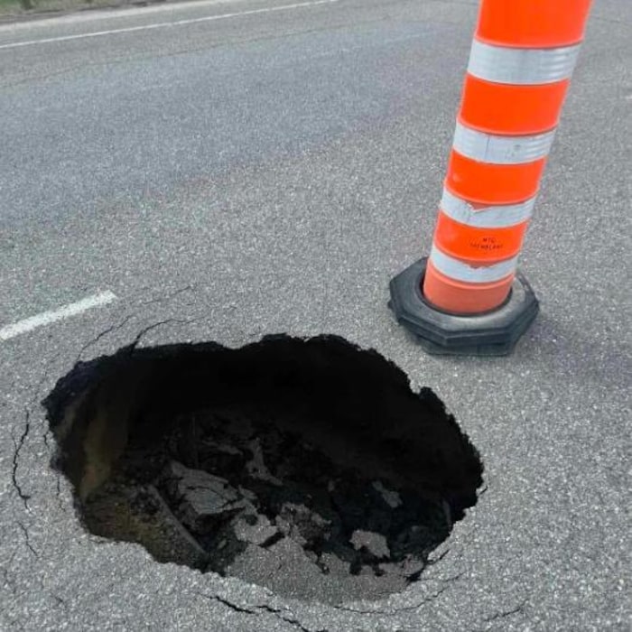 Un cône est placé près d'un trou dans la chaussée de la route 117.