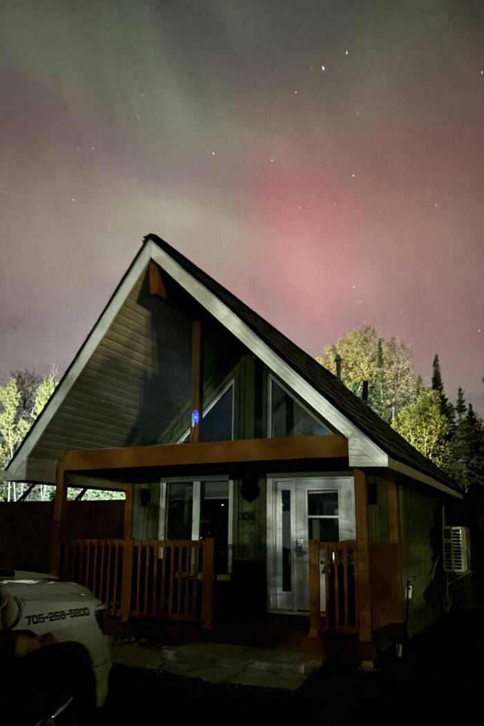 Des aurores boréales au-dessus d'un chalet.