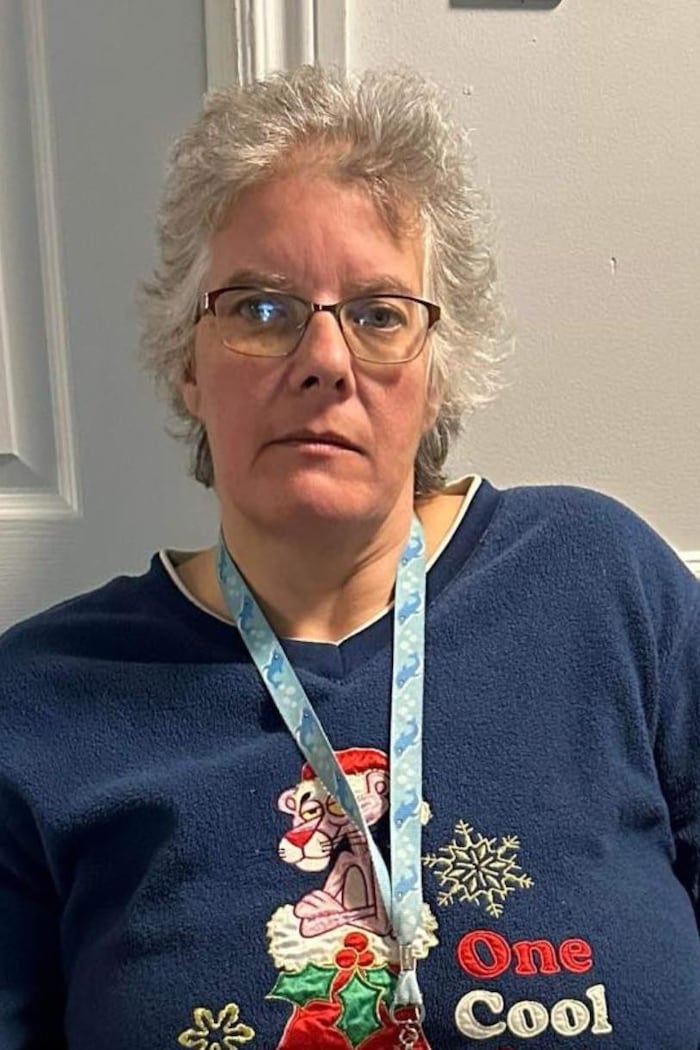 Une femme avec des lunettes et un chandail de Noël.