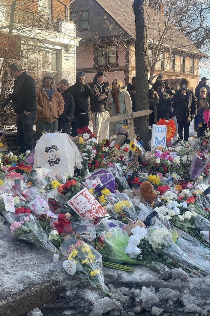Des manifestants derrière l'endroit où des gerbes de fleurs et des peluches ont été déposées.