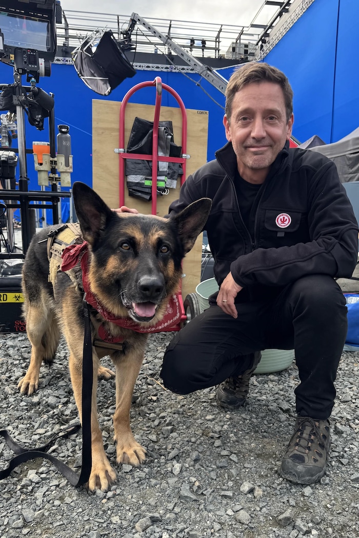 Un homme pose avec un chien.