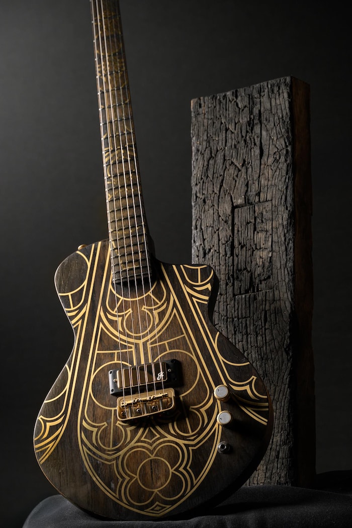 Une guitare électrique est posée à côté d'un morceau de bois brûlé.