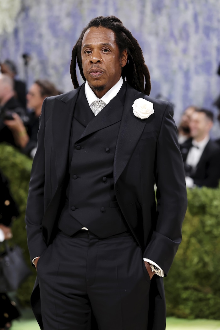 Un homme en costume sombre pose. 