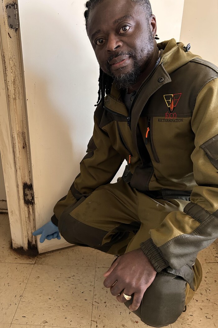 Peter Kabala montre les taches laissées par les punaises au bas d'un cadre de porte.