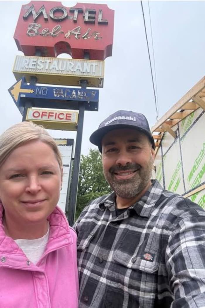Deux personnes se prennent en photo devant une enseigne ancienne.