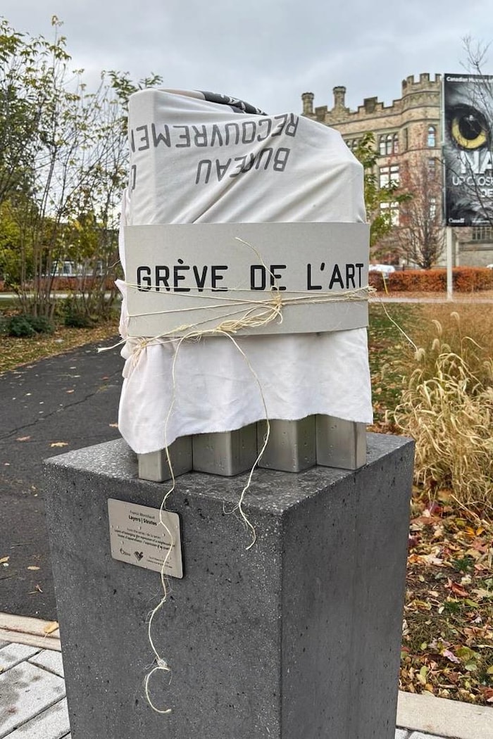 Dehors, une sculpture est recouverte d'un drap blanc et d'un panneau avec la notation « grève de l'art ».