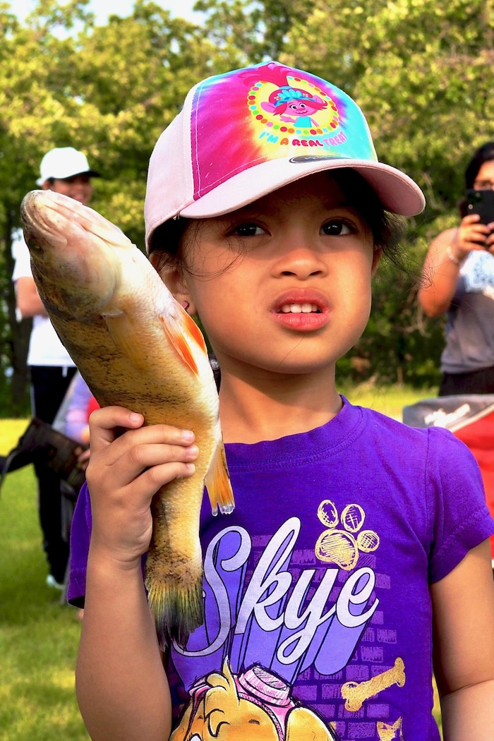 Une fille tient un poisson dans les mains.