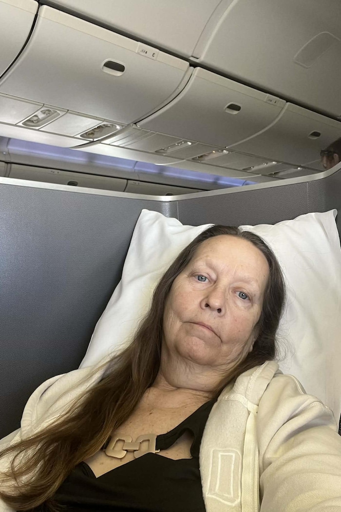 Une femme est allongée dans le siège d'un avion en classe affaires.