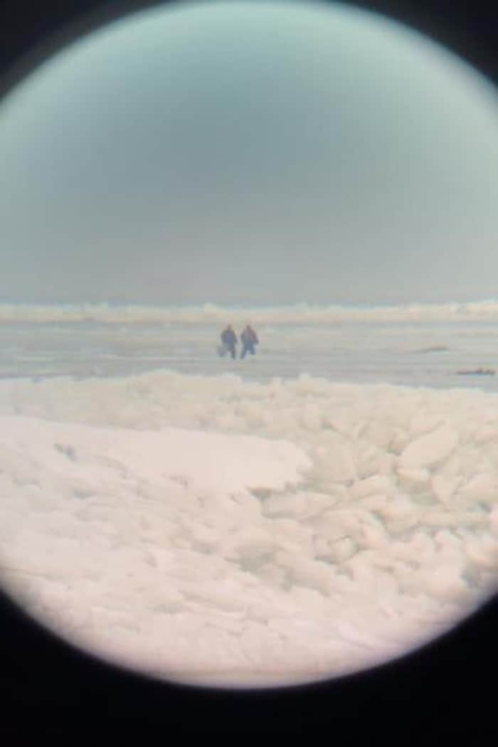 Deux personnes et un chien vus de très loin.