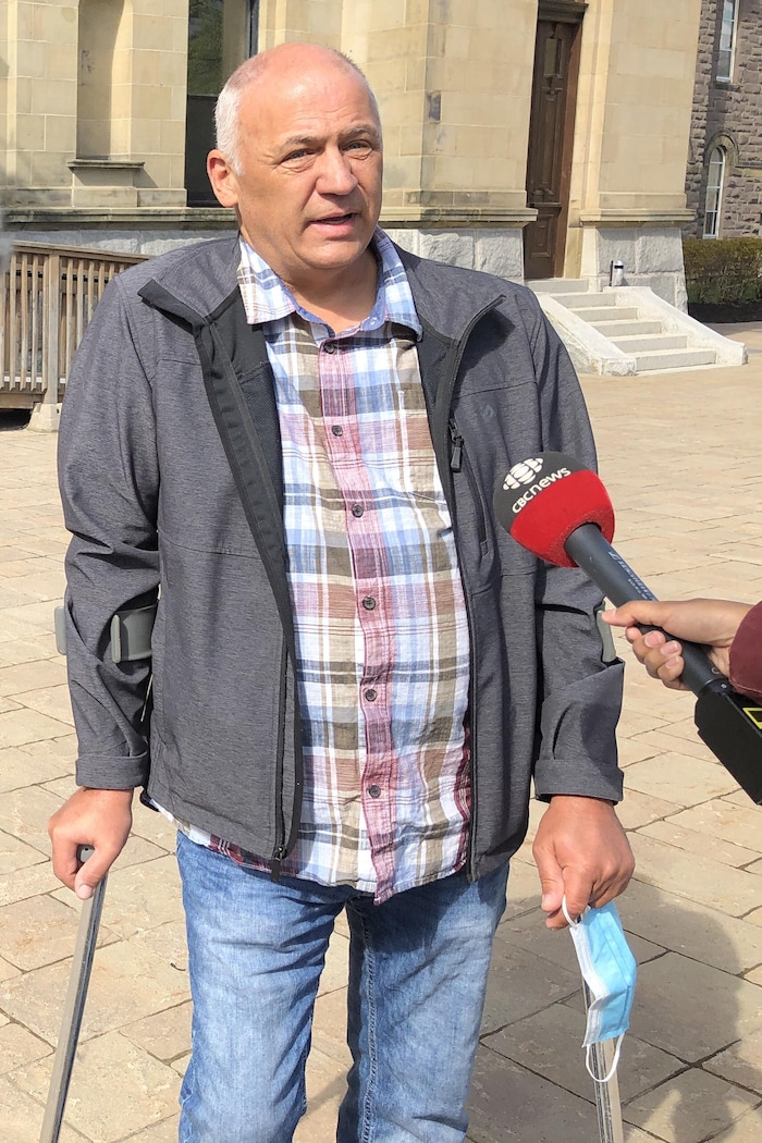 Un homme debout à l'extérieur devant des caméras et des micros.