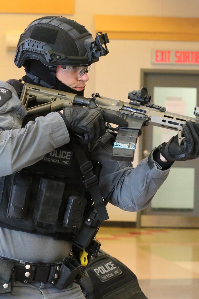 Un agent de police tient une arme dans les mains.