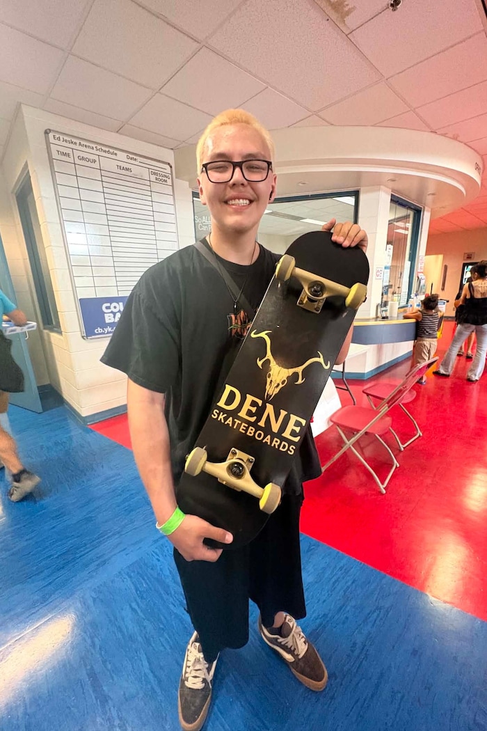 Nateyaa Tanche tient une planche à roulettes sur laquelle est inscrit « Dene Skateboard ».