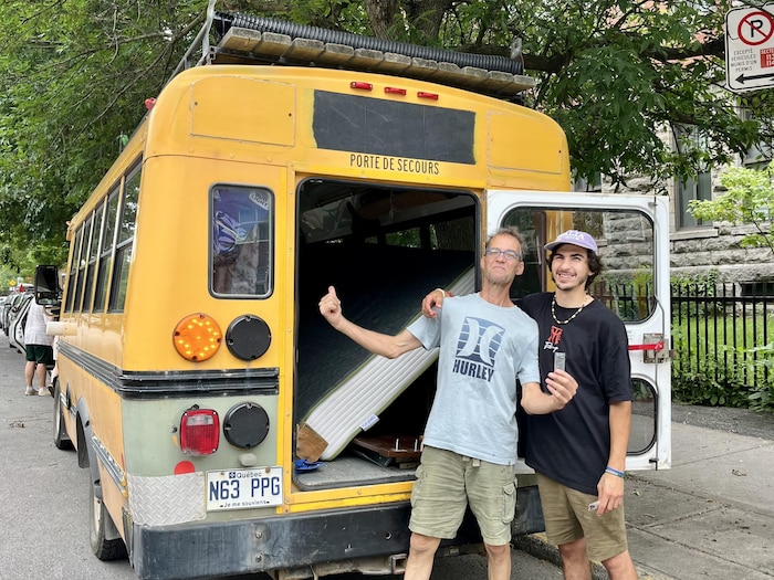 Deux hommes derrière un autobus dont la porte arrière est ouverte.
