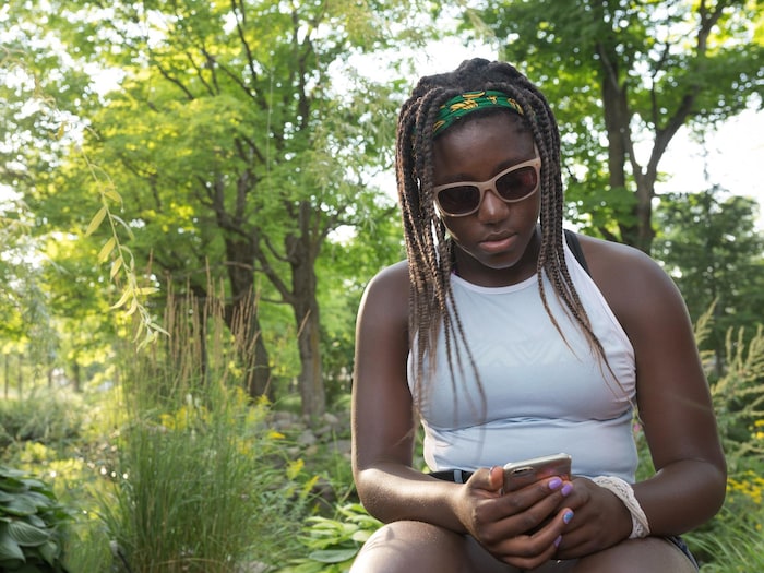 Une adolescente regarde son téléphone dans un parc.