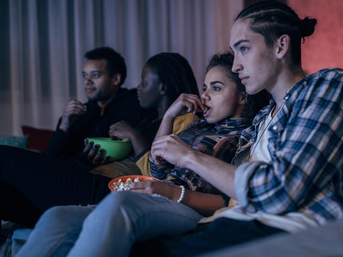 Quatre adolescents regardent un film en mangeant du pop-corn.