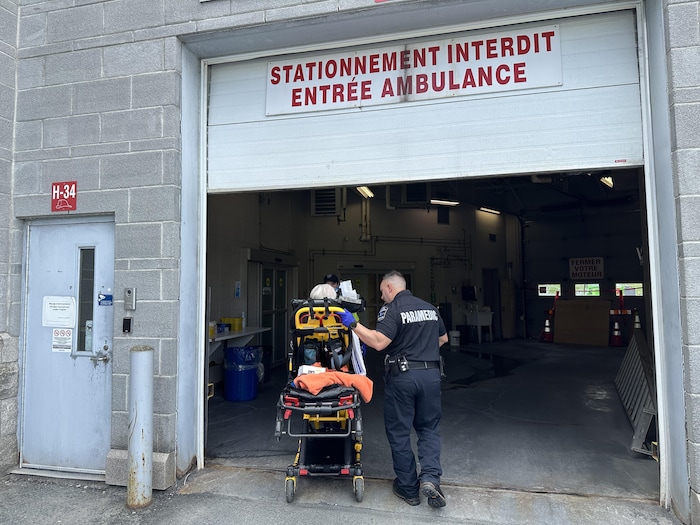 Une ambulance tire une civière vers un garage.