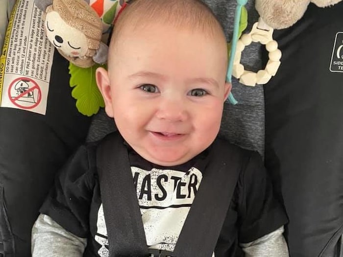 La photo d'un enfant de huit mois dans son siège d'auto, souriant.