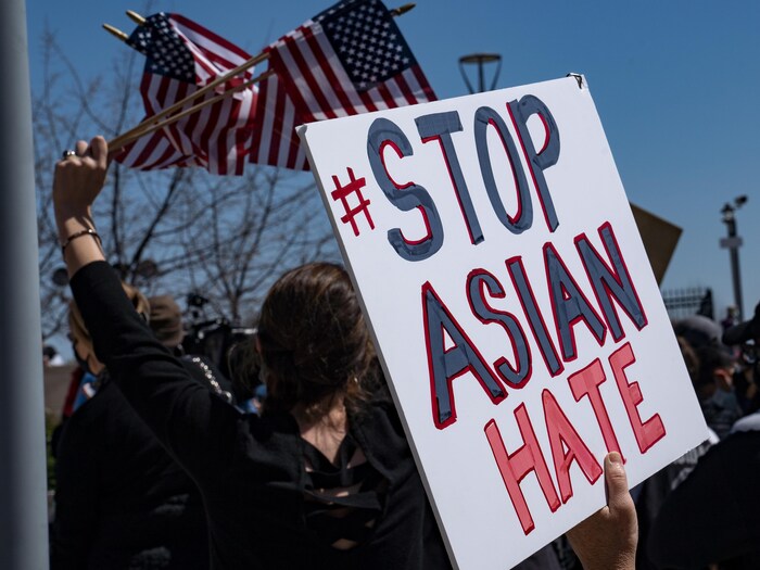 Une personne tient une pancarte sur laquelle il est écrit : Stop Asian Hate (Arrêtez la haine contre les Asiatiques).