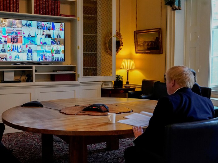 Boris Jonhson assis à une table ronde devant un écran affichant ses homologues du G20.