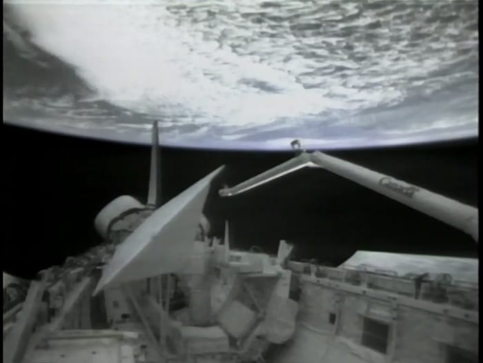 Vue du bras canadien dans l'espace attaché à la navette Columbia avec la Terre en arrière-plan.