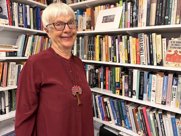 Une femme souriante posant devant une bibliothèque.