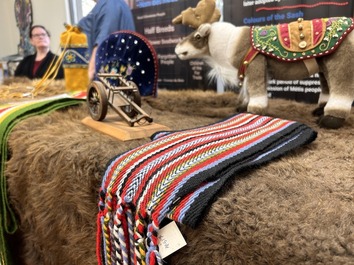 Une ceinture fléchée, un chariot miniature et des œuvres de perlage placé sur une peau de bison.
