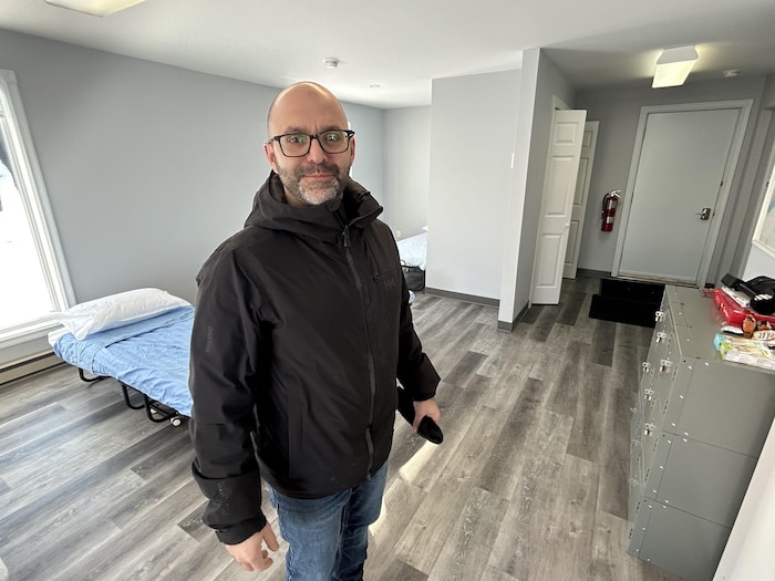 Un homme dans une salle avec des lits.