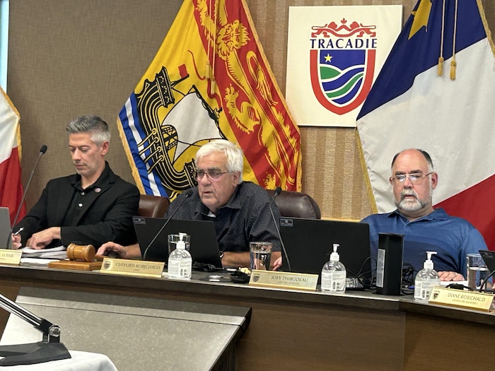 Trois hommes assis derrière une table.