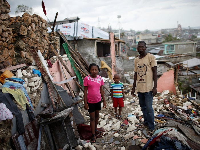 Une famille haïtienne désemparée prend la pose parmi les décombres de sa maison, après l'ouragan Matthew en 2016.
