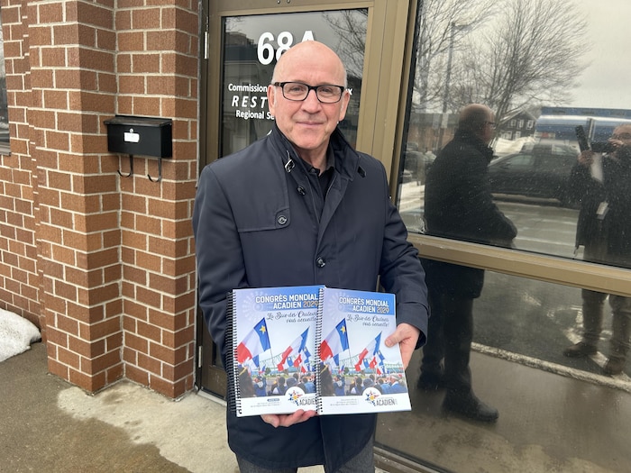 Un homme tient deux cahiers.