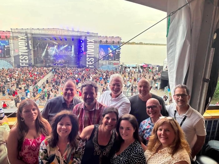 Plusieurs personnes sourient devant la scène du FestiVoix.