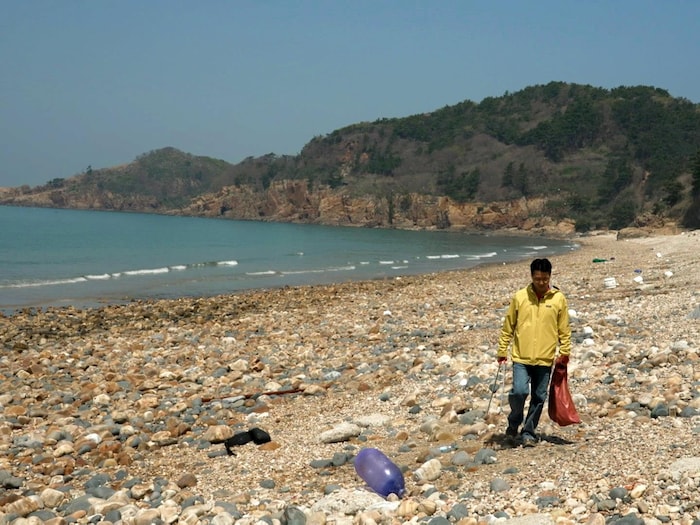 Kang Dong-Wan scans waste on a beach. understand life north korea thanks