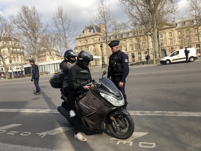 Un agent parle demande ses papiers à un motocycliste.