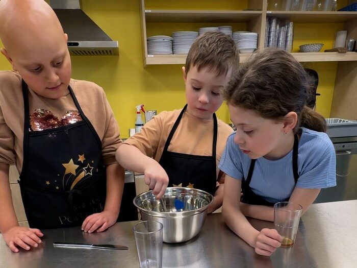 Trois enfants sont rassemblés autour d'un bol à mélanger.