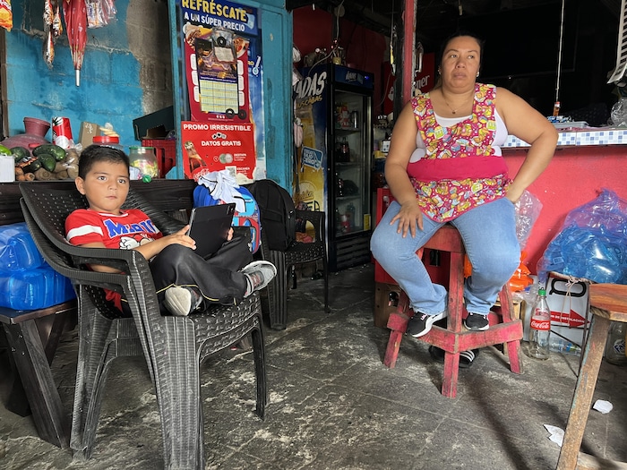 Une femme assise sur un tabouret dans un commerce sombre.