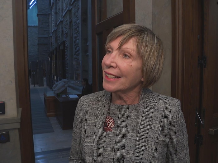 Eleanor Olszewski est debout devant une porte, dans le parlement à Ottawa.