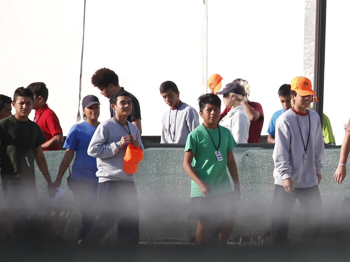 Des enfants migrants  marchent près de tentes dans un centre de détention aux États-Unis