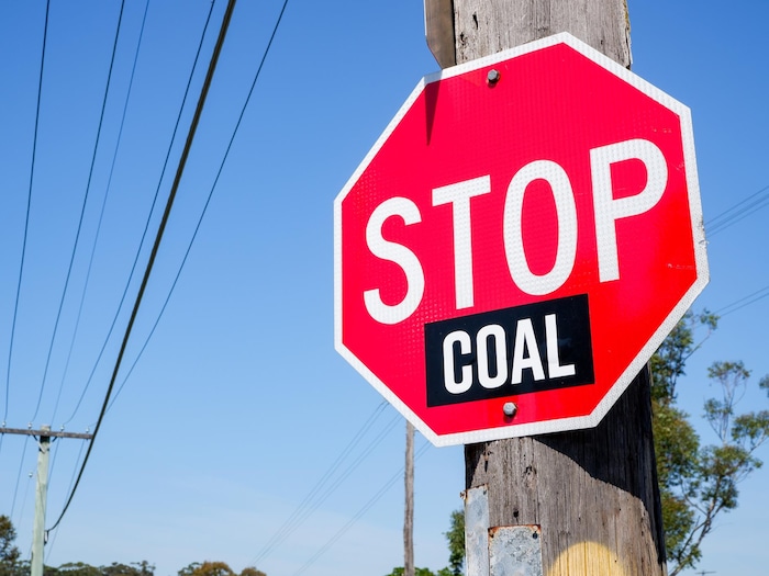 Une pancarte d'arrêt sur laquelle on a ajouté le mot "charbon". 