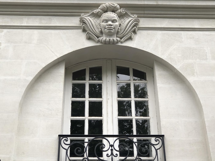 Une tête sculptée dans la pierre incrustée au-dessus d'une fenêtre.