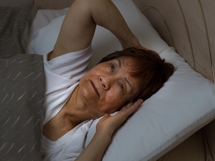 Une femme éveillée dans un lit.