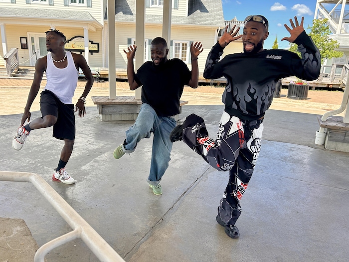 Trois hommes dansent dans la rue.