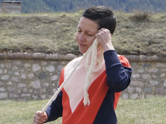 Florentine Rey est sur le site d'un fort historique et porte un vêtement bleu, blanc, rouge. Elle place contre son oreille une grosse corde blanche.