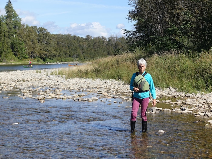 Francine Lévesque est debout, les pieds dans la rivière. 