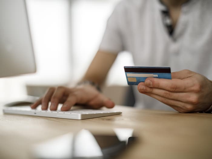 Someone checking their credit card in front of their computer.