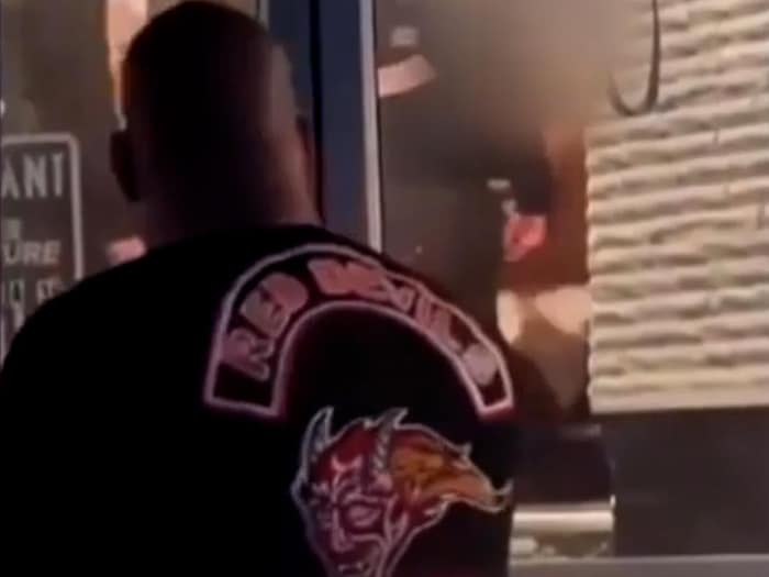 Un homme de dos, vêtu d'un chandail des « Red Devils », se tient devant l'entrée d'un édifice.