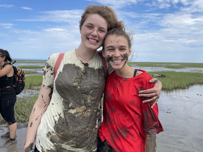 Deux adolescentes couvertes de boue sourient au photographe.